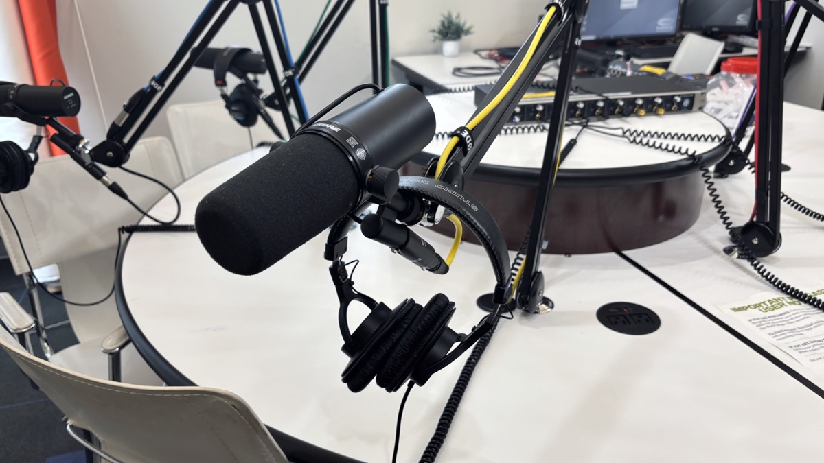 Podcast studio microphones and headphones on a recording table.